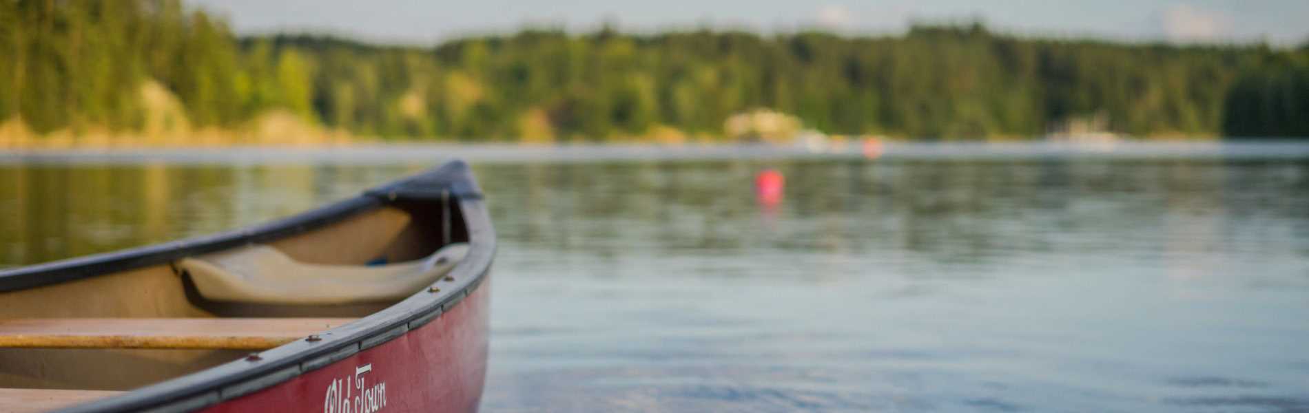 canoe sur l'eau avec paysage flouté en fond, camping la jaougotte