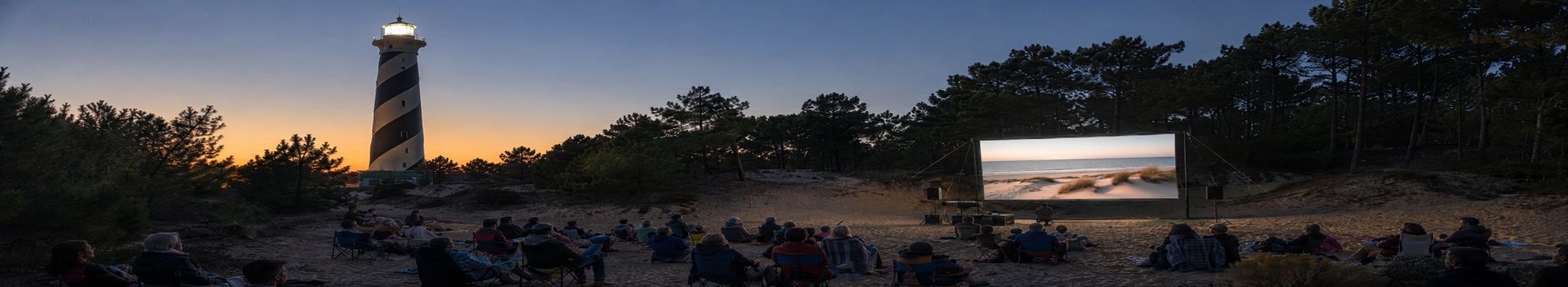 Écran de cinéma en plein air dressé dans les dunes au pied d’un phare landais, au coucher du soleil